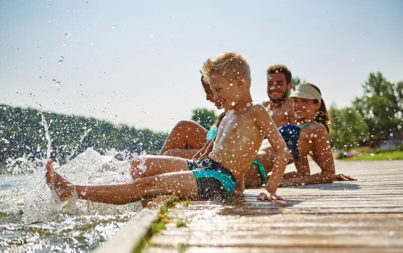 Happy family at a lake having fun and splashing water in summer