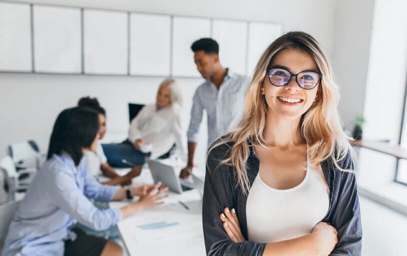 Woman smiling in conference room with four employees in the background