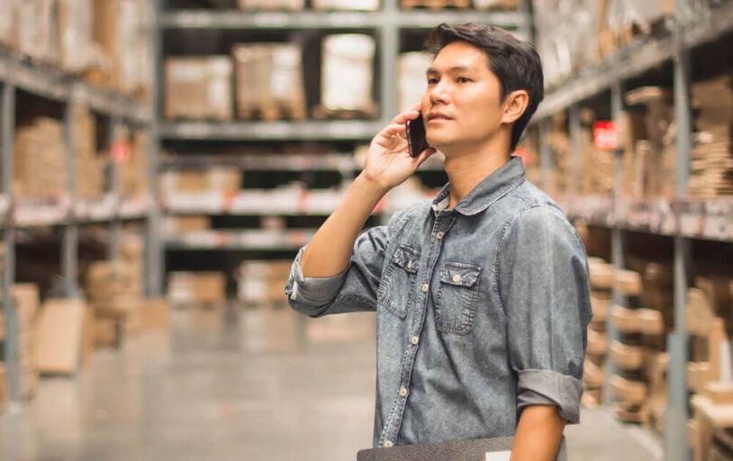 Man standing in warehouse talking on a cell phone