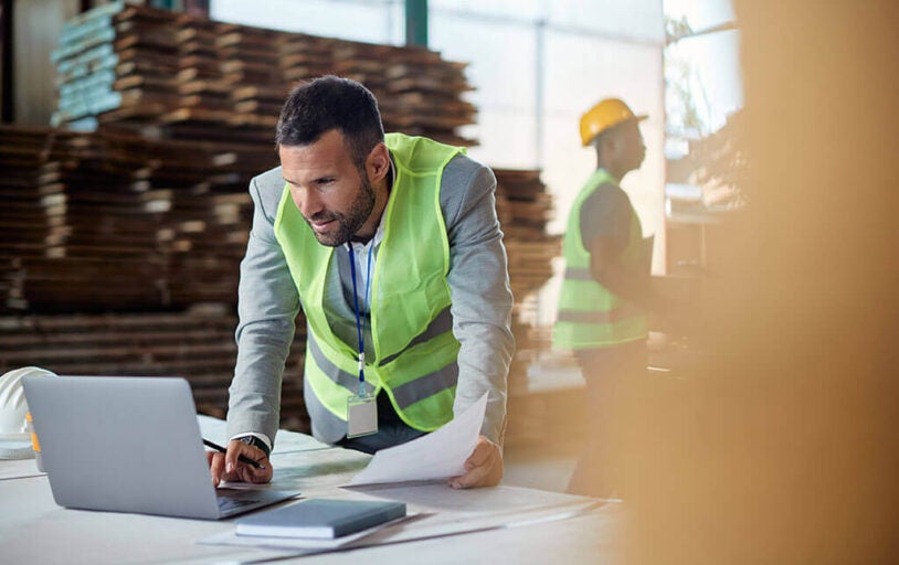 Man in a warehouse leaning over a laptop